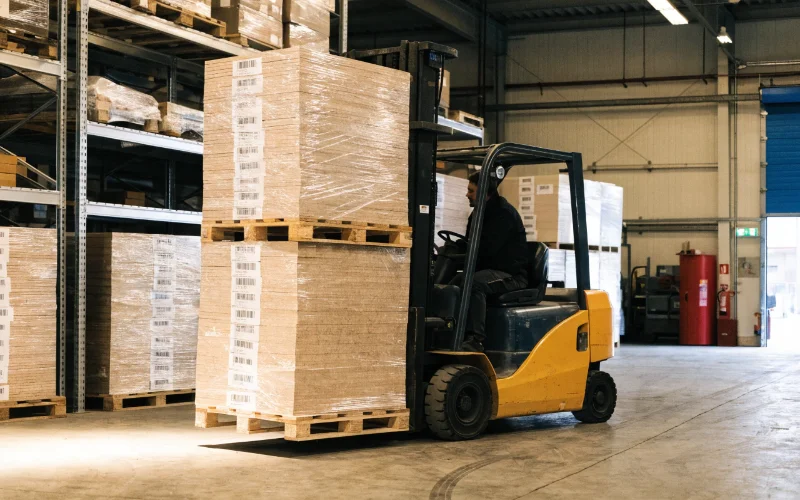 A forklift moving palettes of neatly packed MDF frames in a warehouse, symbolizing efficient logistics